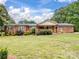 View of brick home with covered porch, surrounded by lush landscaping, showcasing a serene backyard at 895 Furnace Rd, Iron Station, NC 28080