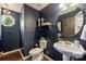 Stylish powder room with a pedestal sink, dark walls, decorative mirror, and unique lighting fixtures at 9209 Cameron Wood Dr, Charlotte, NC 28210