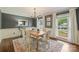 Well-lit dining room with gray walls, white trim, large windows with curtains, and a rustic wooden table at 9209 Cameron Wood Dr, Charlotte, NC 28210