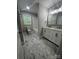 Well-lit bathroom with a double vanity, bathtub, and marble-look tile flooring at 117 Woodland Ave, Shelby, NC 28152