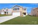 Two-story home with a two-car garage, stone accents, neutral siding, and a well-manicured lawn under a bright, blue sky at 14026 Wilson Mac Ln, Charlotte, NC 28278