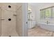 Bathroom showcasing walk-in shower, freestanding tub, granite counters, wood look tile floors, and bright natural light at 1655 Buckland Ct, Indian Land, SC 29707