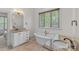 Bright bathroom featuring a standalone tub, double granite vanity, wood look tile floors, and a window with natural light at 1655 Buckland Ct, Indian Land, SC 29707
