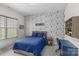 This bedroom features a blue quilted bedspread, unique wallpaper and stylish accents, perfect for a space at 1655 Buckland Ct, Indian Land, SC 29707