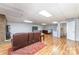 Open-concept basement with brick fireplace, wood-look flooring, and access to a bathroom and bedroom at 174 Wintergreen Cir, Statesville, NC 28677