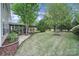 Well-manicured backyard featuring lush green grass, mature trees, and a screened-in porch at 2218 Legacy Oak Dr, Waxhaw, NC 28173