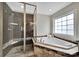 Modern bathroom with a glass-enclosed shower and luxurious soaking tub under a bright window at 2218 Legacy Oak Dr, Waxhaw, NC 28173