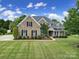 Charming two-story brick home with manicured lawn, lush landscaping, and classic black shutters offers elegant curb appeal at 2218 Legacy Oak Dr, Waxhaw, NC 28173