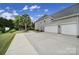 Side exterior featuring a three car garage, mature landscaping, and driveway at 2218 Legacy Oak Dr, Waxhaw, NC 28173