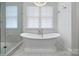 Bright bathroom featuring a freestanding soaking tub, a window, and a glass-enclosed shower at 2309 Ethan Way, Weddington, NC 28104
