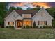 Charming brick home featuring manicured landscaping, warm exterior lighting, and a beautiful sunset backdrop at 2309 Ethan Way, Weddington, NC 28104