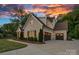 Charming two-story white brick home with a three-car garage and manicured landscaping under a vibrant sunset at 2309 Ethan Way, Weddington, NC 28104