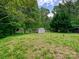Large, grassy backyard featuring a storage shed and mature trees, offering plenty of space at 2544 Cedarwild Rd, Charlotte, NC 28212