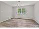 Bright bedroom featuring two large windows, gray walls, stylish light fixture, and modern flooring at 2544 Cedarwild Rd, Charlotte, NC 28212