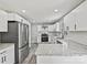 Modern kitchen featuring stainless steel appliances, white cabinets, granite countertops, tile backsplash, and stylish flooring at 2544 Cedarwild Rd, Charlotte, NC 28212