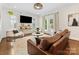 Bright living room with white walls, hardwood floors, a stylish ceiling fan, and a comfortable brown leather couch at 3101 Auburn Ave, Charlotte, NC 28209