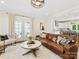 Living room featuring a leather couch, bright windows, a round coffee table, and an open view to the kitchen at 3101 Auburn Ave, Charlotte, NC 28209