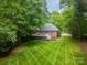 Aerial view of a lush backyard with a manicured lawn, deck, patio, and wooded surroundings at 4033 Weddington Manor Ct, Matthews, NC 28104