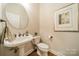 This powder room features a pedestal sink with a round mirror above and modern art on the wall at 4033 Weddington Manor Ct, Matthews, NC 28104