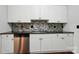 Kitchen features stainless dishwasher, white cabinets, black countertop, and mosaic tile backsplash at 4132 Kenton Glenn Nw Ct, Concord, NC 28027