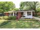 Charming red brick and white home with black shutters and a well-manicured lawn at 4361 Applegate Rd, Charlotte, NC 28209