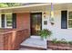 Welcoming front porch with brick accents, a decorative flag, and a potted fern at 4361 Applegate Rd, Charlotte, NC 28209