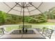Back deck features a table with umbrella and chair set with potted plants on the table and lush green scenery in the background at 4405 Sugar Cane Ct, Waxhaw, NC 28173