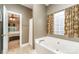 Bright bathroom featuring a soaking tub with a tiled wall and an open doorway to the bedroom at 4405 Sugar Cane Ct, Waxhaw, NC 28173