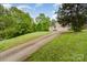 View of the house and long driveway leading up to it from the street through a yard of lush greenery and various trees at 4405 Sugar Cane Ct, Waxhaw, NC 28173