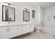 Modern bathroom with double sinks, sleek white cabinetry, gray tile floors, and a glass-enclosed shower-tub combination at 4608 Rockwood Dr, Waxhaw, NC 28173