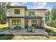 Home's back exterior featuring a stone patio, dining set, mature trees, and outdoor entertaining spaces at 4608 Rockwood Dr, Waxhaw, NC 28173