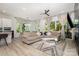 Bright living room features wood floors, modern fan, large windows, and comfortable sectional sofa at 4608 Rockwood Dr, Waxhaw, NC 28173