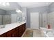 Bathroom featuring double sink vanity, large mirror, soaking tub, and glass enclosed shower at 52538 Winchester St, Fort Mill, SC 29707
