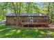 View of backyard showcasing brick home, deck, and grassy lawn with a fenced area at 606 Deer Creek Dr, Matthews, NC 28105