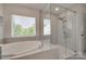 Bright bathroom features a soaking tub, walk-in shower, and a view of the lush greenery at 6176 Russo Ct, Lancaster, SC 29720