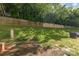Fenced backyard area with a gentle slope, green grass, and mature trees for added privacy at 6912 Park Place Dr, Charlotte, NC 28262