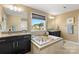 Bright bathroom with large tub situated between two granite-topped vanities at 7216 Old Valley Way, Harrisburg, NC 28075