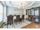 Elegant dining room featuring a chandelier, rich hardwood floors, and a built-in china cabinet for storage and display at 8709 Barrelli Ct, Charlotte, NC 28277