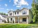 Charming two-story home with neutral siding, black trim, front porch, and well-manicured lawn at 8717 Lawyers Rd, Charlotte, NC 28227