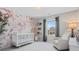 A bright, cozy Bedroom with a white crib, accent chair, floral wallpaper, and ample natural light at 1005 Cheviot Ct, Waxhaw, NC 28173