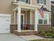 Covered front porch with brick accents, white columns, and an American flag at 1005 Cheviot Ct, Waxhaw, NC 28173