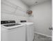 Well-lit laundry room featuring white washer and dryer set, wire rack shelving, and gray tile floor at 1005 Cheviot Ct, Waxhaw, NC 28173