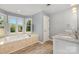 Bright bathroom featuring a soaking tub with marble surround and wood-look tile flooring at 109 Arabian Ln, Salisbury, NC 28147