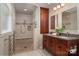 Well-lit bathroom with a glass-enclosed shower, dual sinks, and wood cabinetry at 1260 Piccadilly Dr, Charlotte, NC 28211