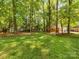 Large grassy backyard lined with mature trees and a home with a red brick facade in a tranquil environment at 1325 Rock Point Rd, Charlotte, NC 28270