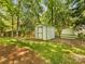 Storage shed surrounded by trees and lush green lawn in a fenced backyard at 1325 Rock Point Rd, Charlotte, NC 28270