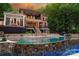 A large home overlooks the in-ground pool with a stone waterfall and a covered patio with a pergola at 135 Sumter Dr, Mooresville, NC 28117