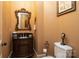 Elegant powder room with ornate mirror, beautiful vanity with dark wood and toilet with decorative accents at 135 Sumter Dr, Mooresville, NC 28117
