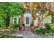 Inviting brick front entrance with decorative foliage, a storm door, and a clear house number above the doorway at 15000 Strathmoor Dr, Charlotte, NC 28277
