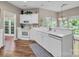 Bright kitchen featuring white cabinetry, hardwood floors, a breakfast bar, and a view of the backyard at 15000 Strathmoor Dr, Charlotte, NC 28277